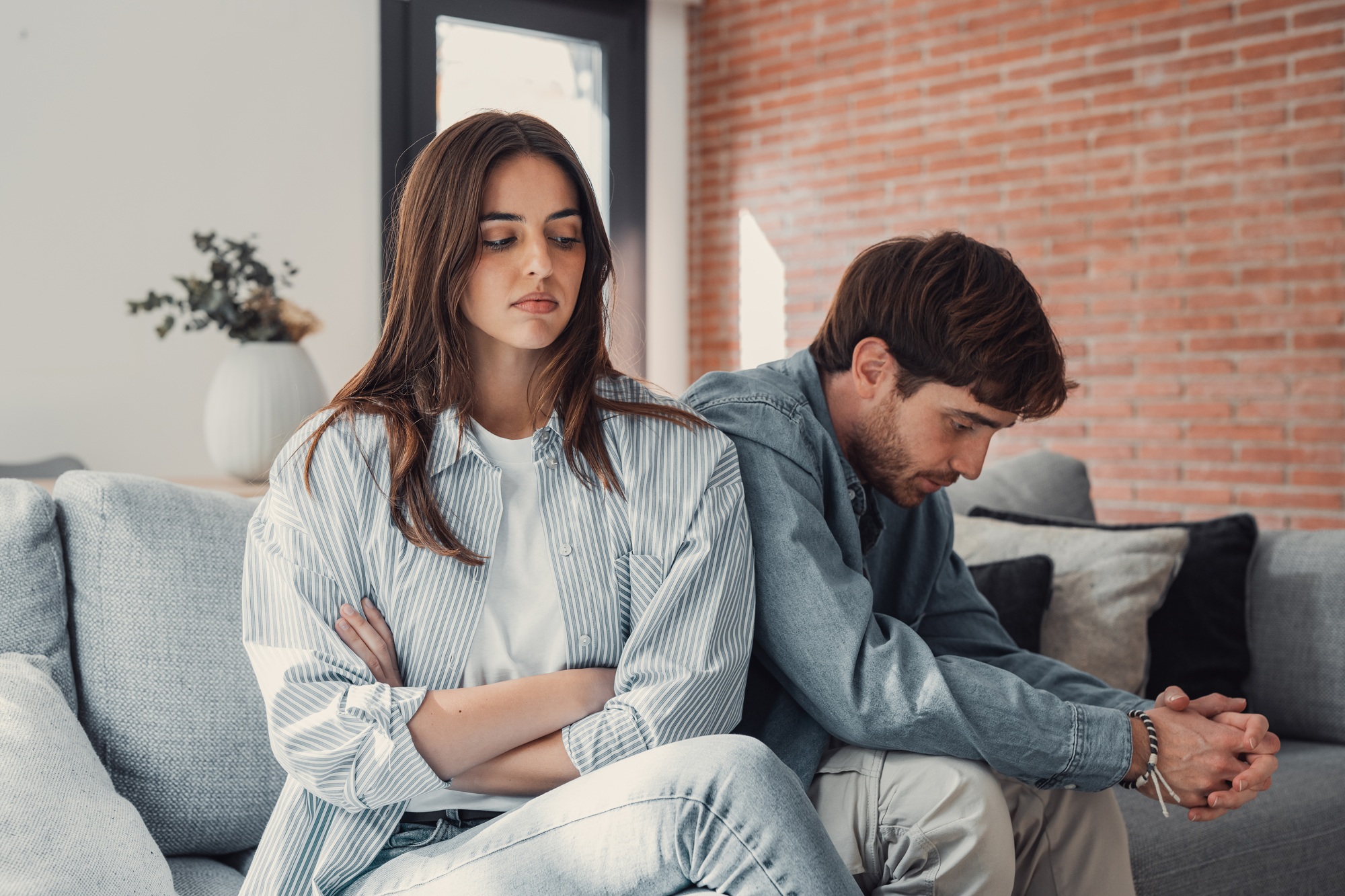 Beautiful lady is depressed, sitting on the couch talking to man, having a dispute with husband